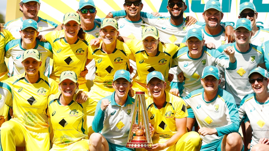 Australia's players and coaches huddle for a group photo with the Women's Ashes trophy