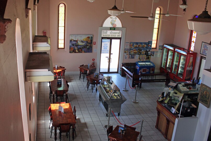 The inside of a former stone church with restaurant tables and a salad bar.