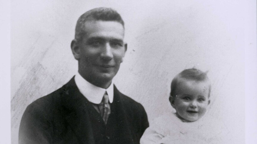 Black and white photo of Dr John Gilruth with his baby daughter on his knee.