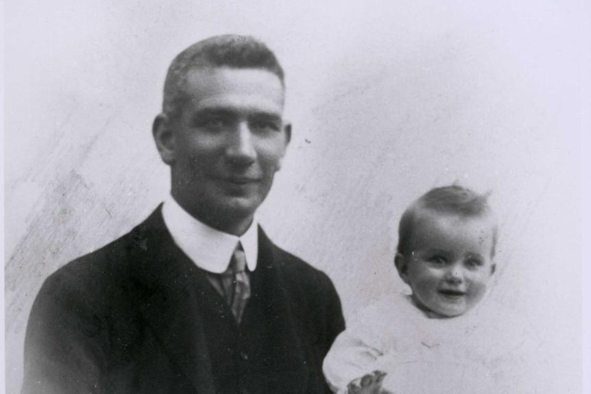 Black and white photo of Dr John Gilruth with his baby daughter on his knee.