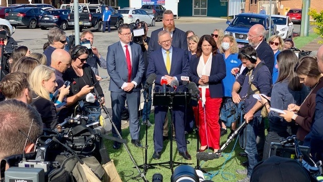 Labor leader Anthony Albanese addresses the media surrounded by people.