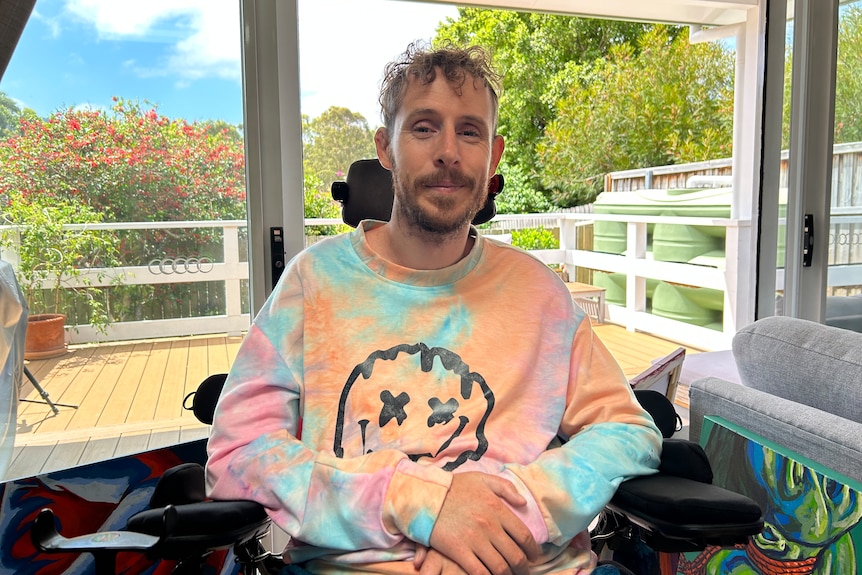 Man in wheelchair smiles in a home