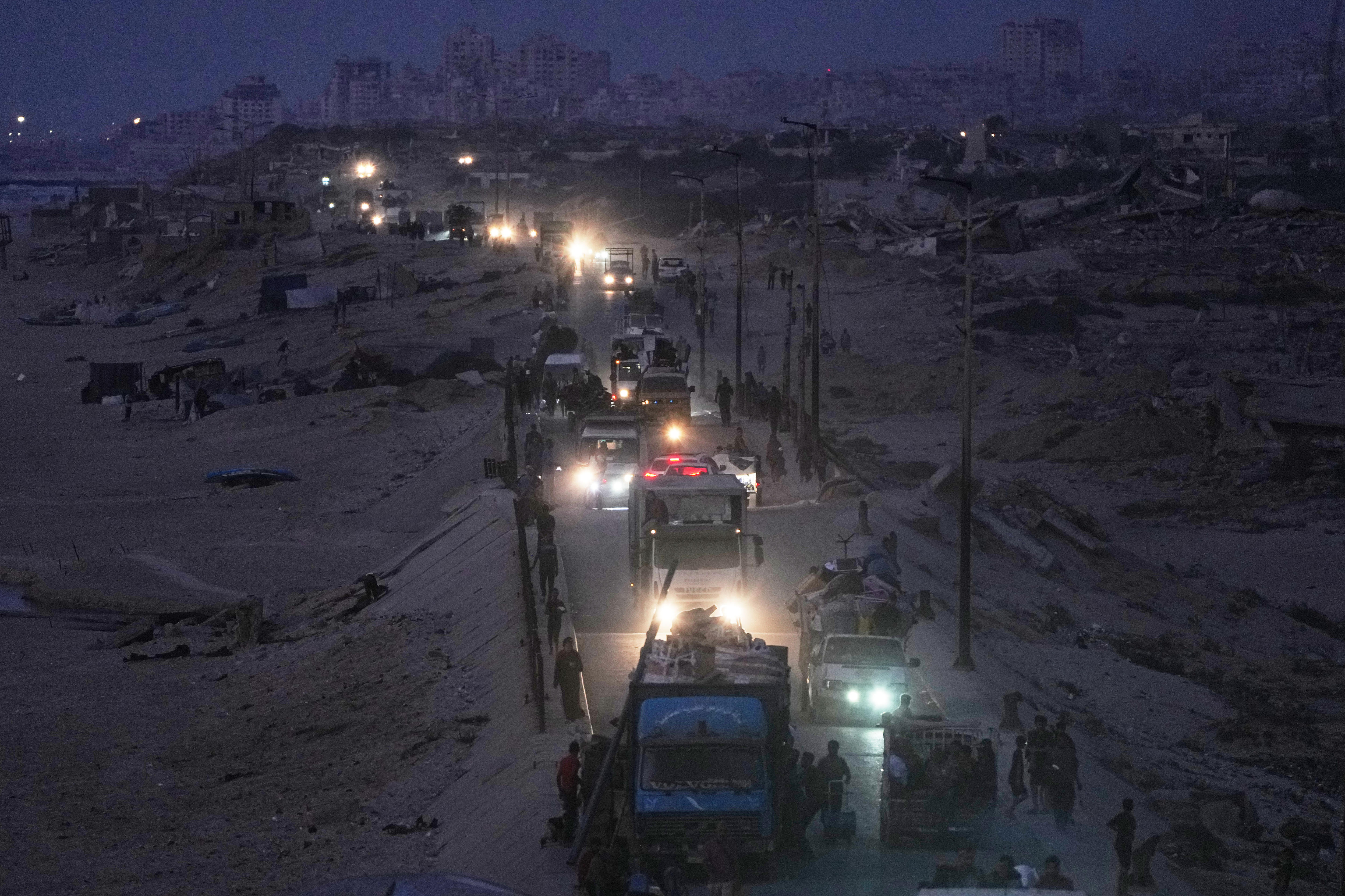 Convoy of cars and truck driving at dawn with headlights flashing.