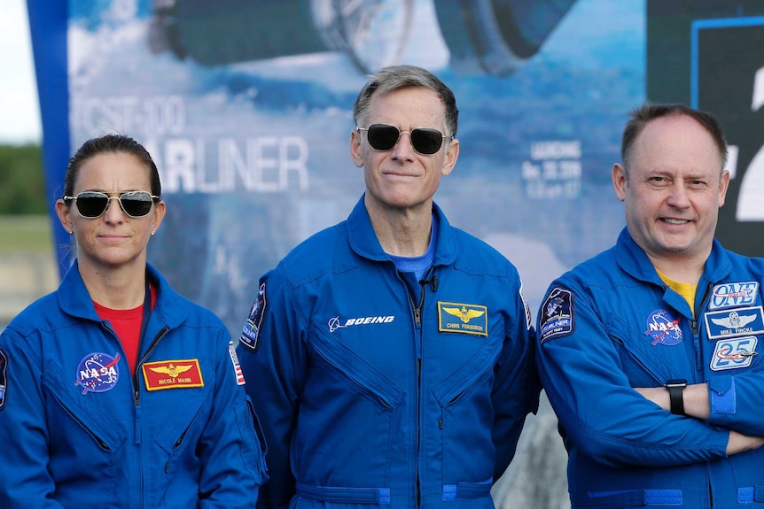 Nicole Mann, Chris Ferguson  and Mike Fincke pose for photo wearing blue jumpsuits.