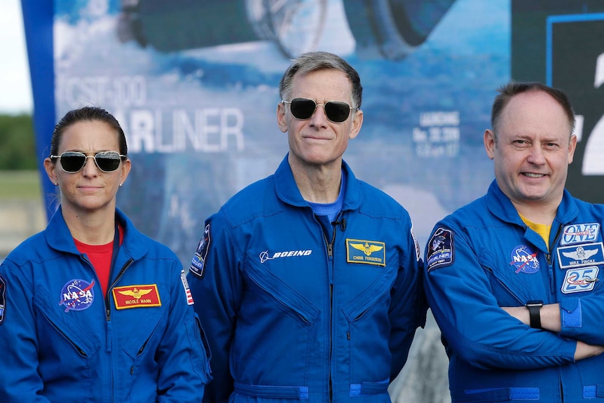 Austonauts Nicole Mann, left, Chris Ferguson, center, and Mike Fincke pose for photo, wearing blue jumpsuits.