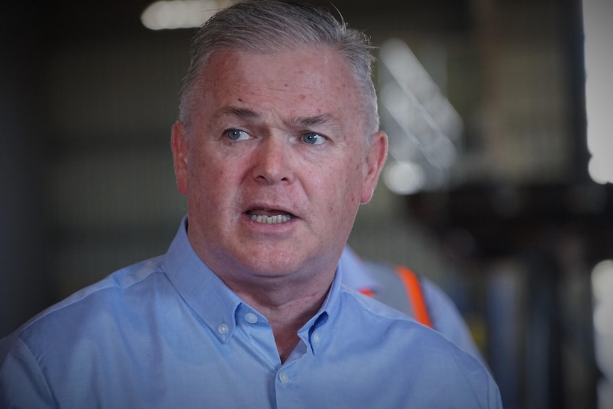 A man, wearing a blue shirt, speaking.