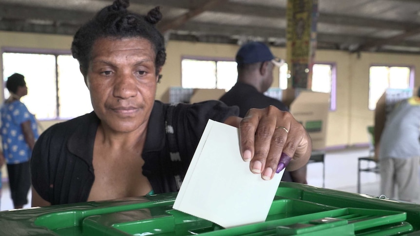 A voter and polling officials at a polling booth at Tokorara High School, Port Moresby.