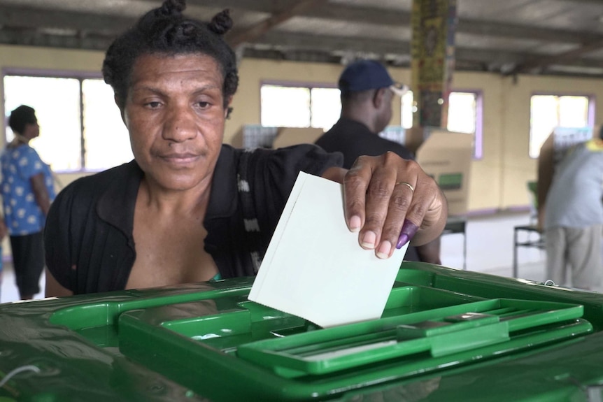 A voter and polling officials at a polling booth at Tokorara High School, Port Moresby.