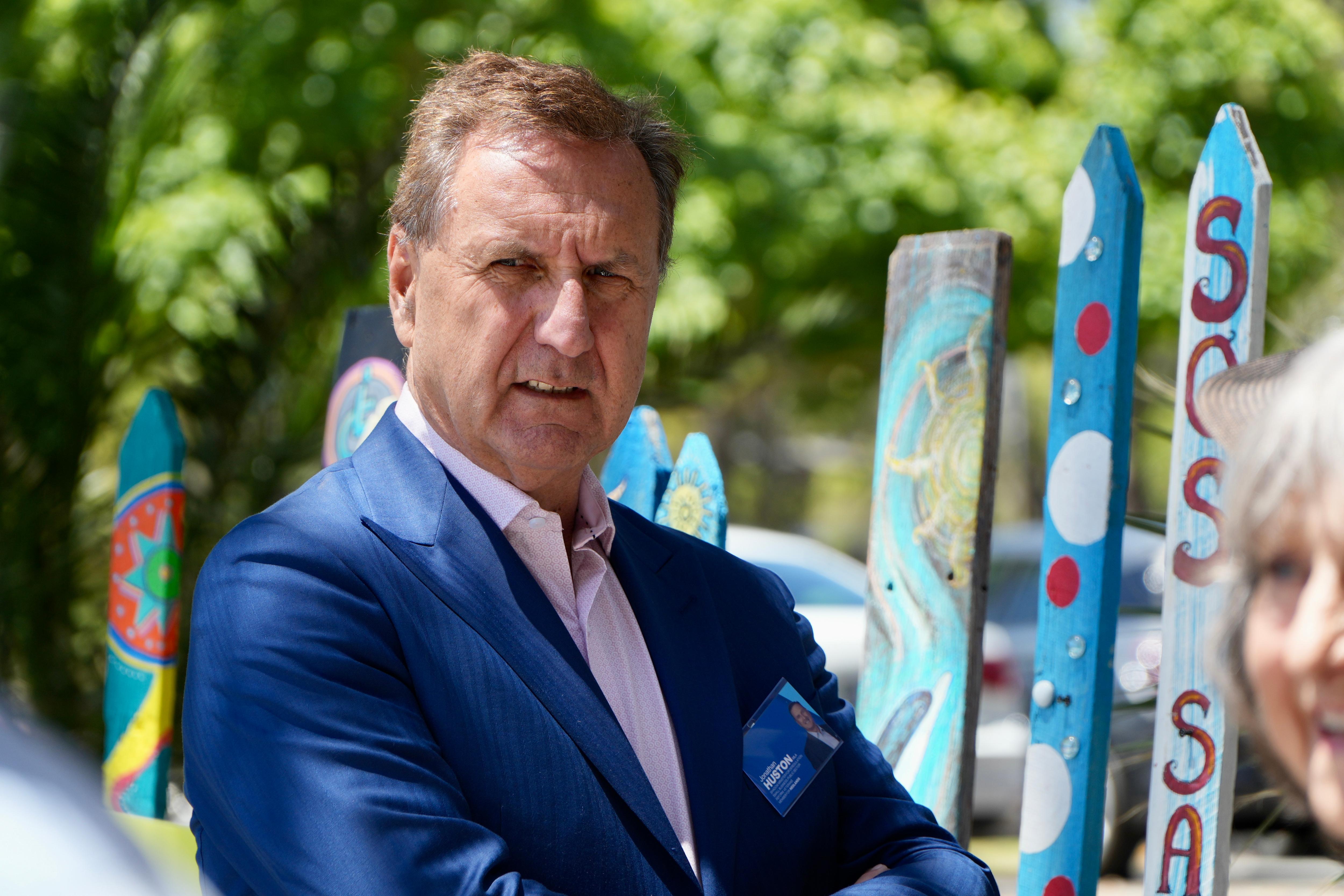Un hombre vestido de azul se encuentra frente a carteles que protestan contra un ferry.