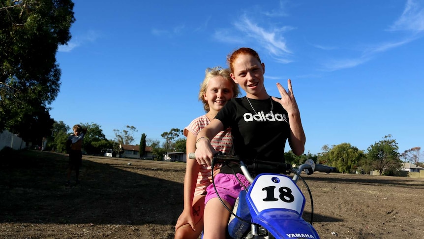 Two girls ride a dirt bike in Moree, NSW