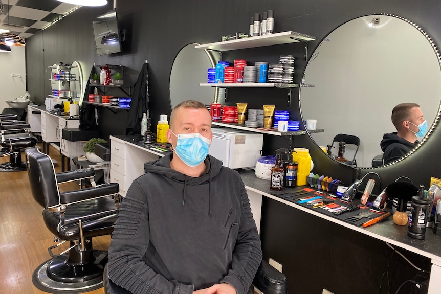 Man sitting in chair at barbershop with mask.
