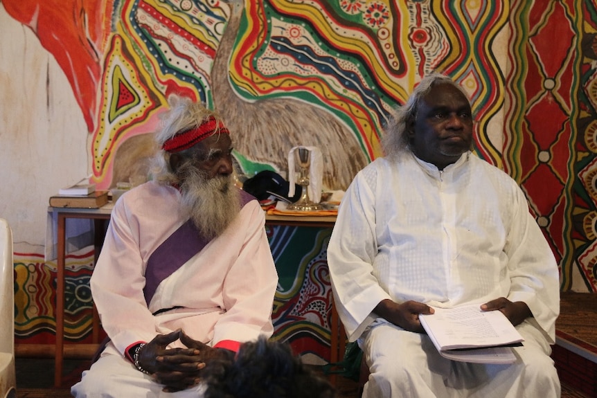 Two men in white clothing at the funeral