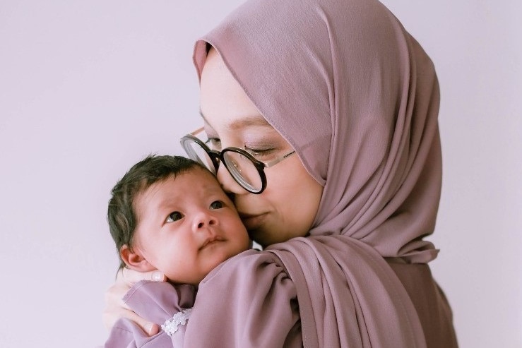 A photo of Indiana, who wears a beige hijab, holding her baby daughter.