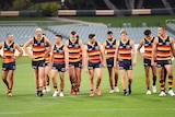 Adelaide Crows players look dejected as they walk off the field in front of empty stands