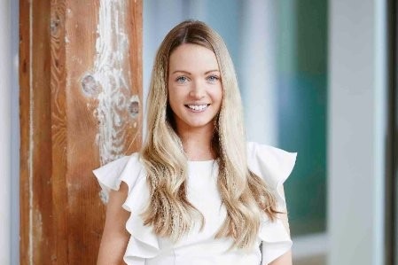 A blonde woman smiles at the camera