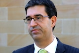 A medium shot of Nick Goiran standing in front of a cream brick wall.