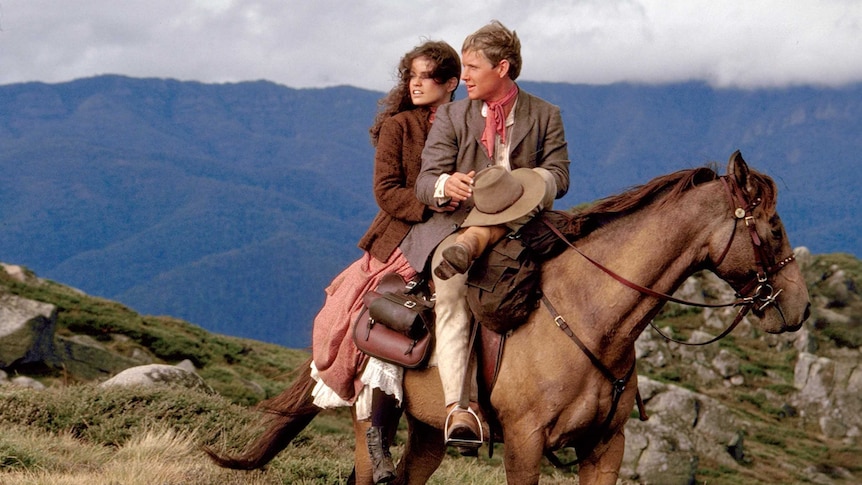 A man and a woman sit on a horse. Still taken from the film the Man from Snowy River.