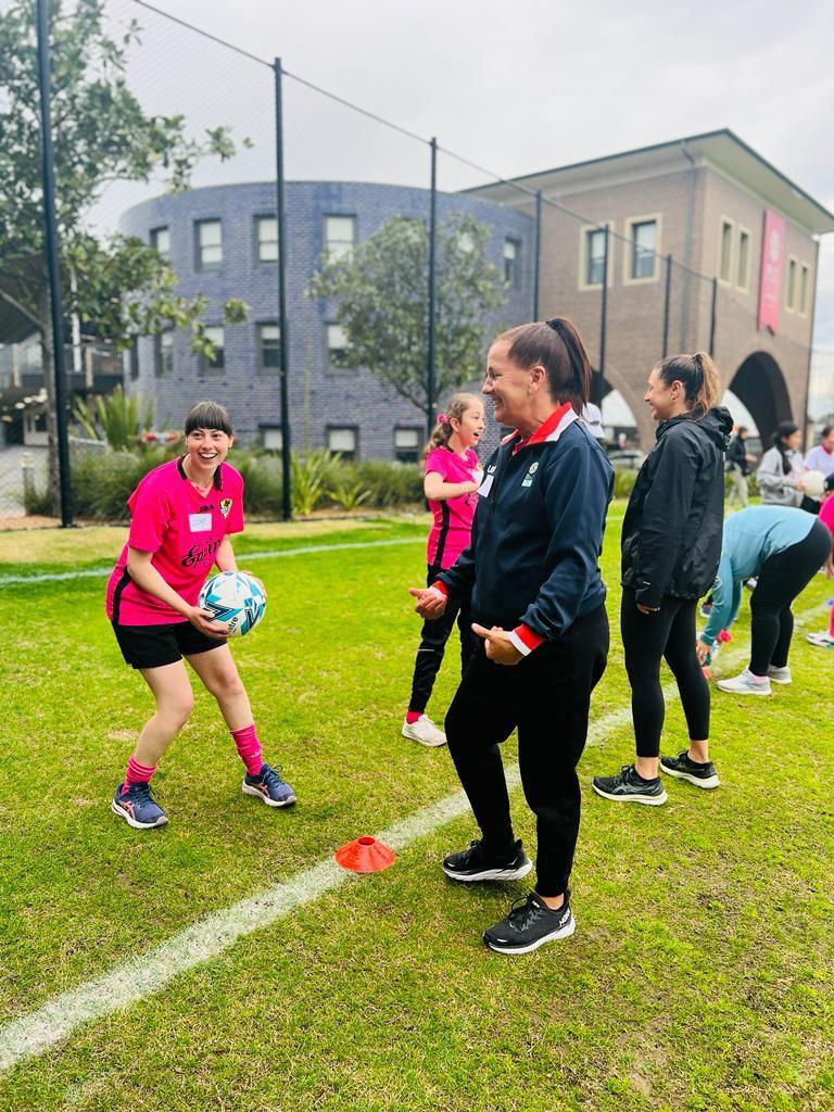 A young woman wearing a pink shirt holds the ball as she plays a game with an older woman wearing a tracksuit