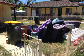 Furniture and rubbish bins fill the front yard of an abandoned home in Bidwill.