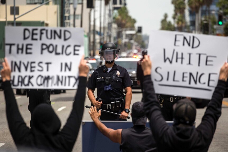Demonstrators holding signs confront a police officer, Tuesday, June 2, 2020, in the Hollywood section of Los Angele