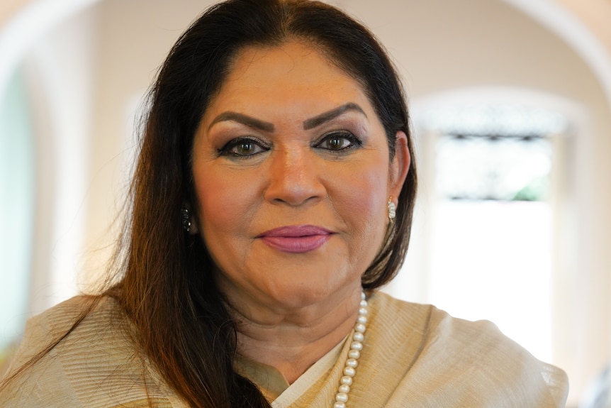 A close up of a woman with dark hair and eyes smiling