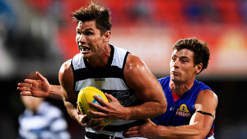 A Geelong Cats AFL player marks the ball with both hands in front of his stomach.