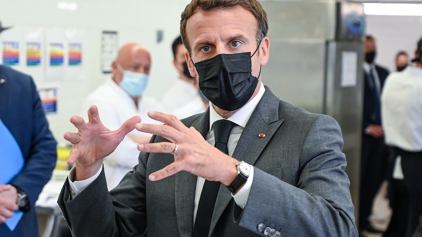 French President Emmanuel Macron wears a dark suit and gestures.