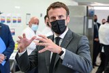 French President Emmanuel Macron wears a dark suit and gestures.