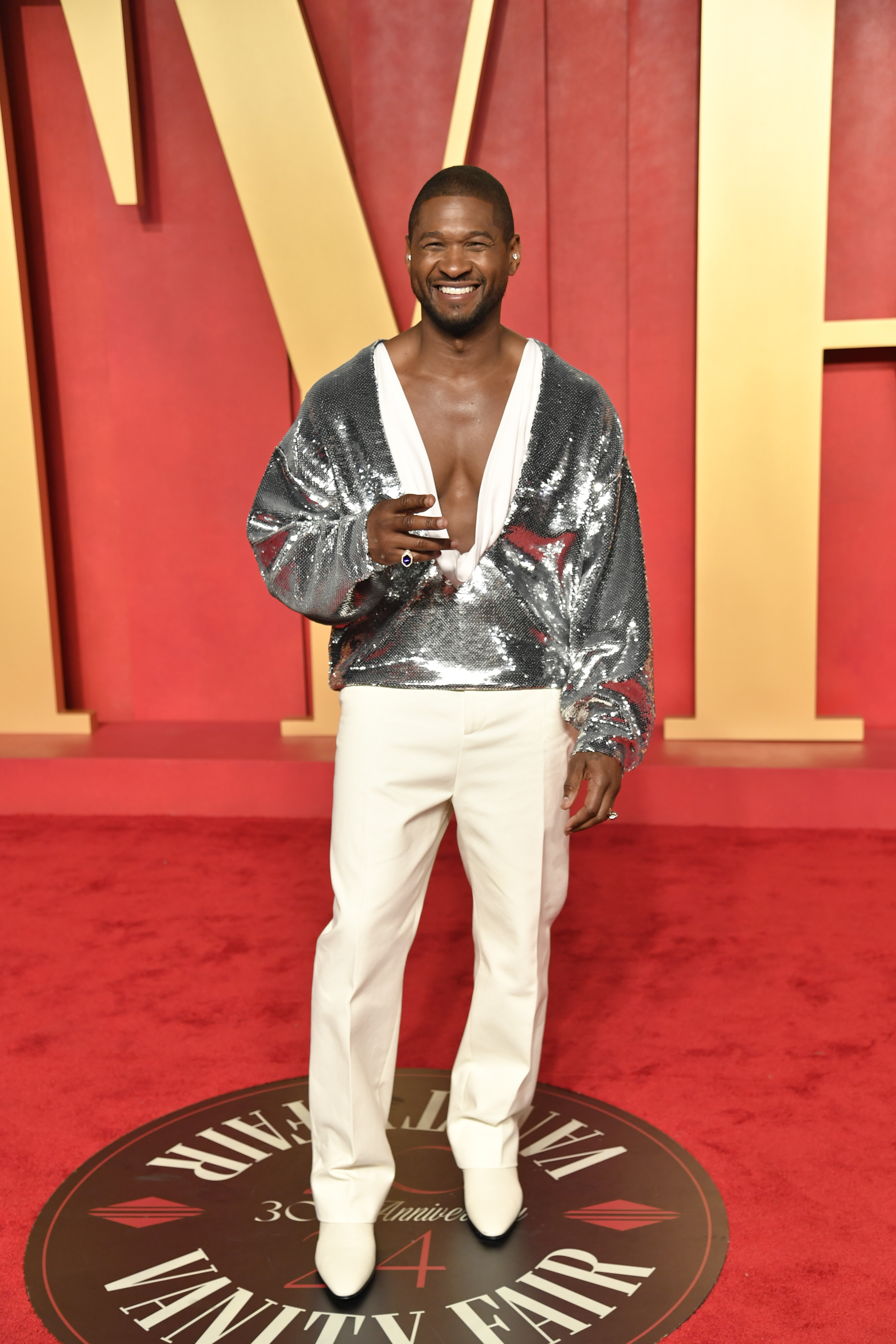 Usher wearing a silverly sparkly suit jacket with white silky trousers
