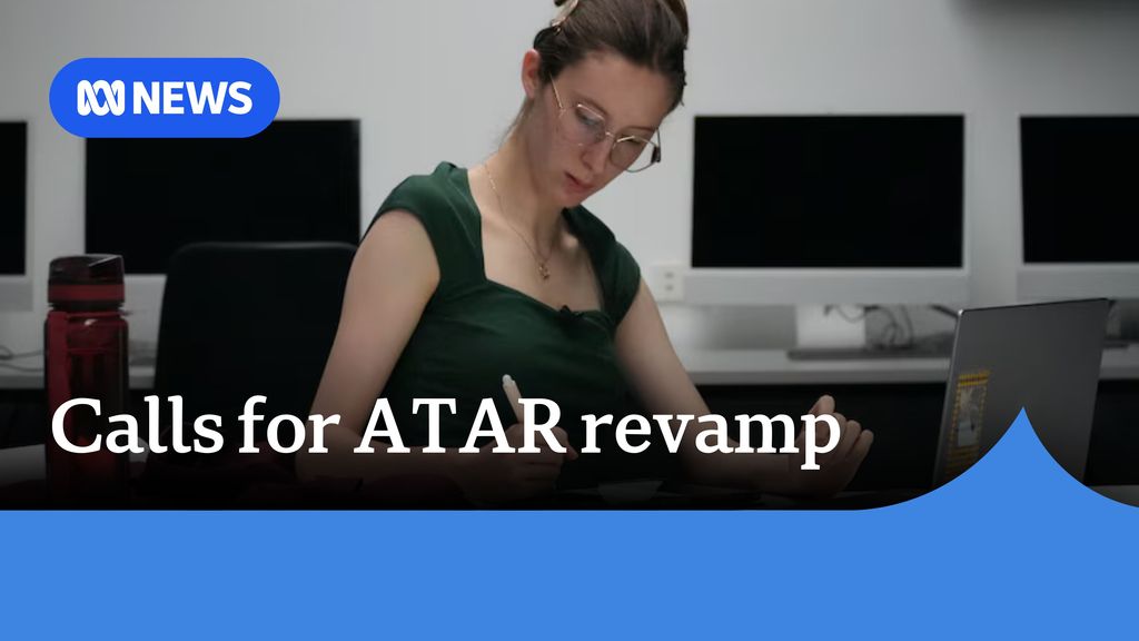 Calls for ATAR revamp: A woman with brown hair tied up writing on paper while seated in front of a laptop computer.