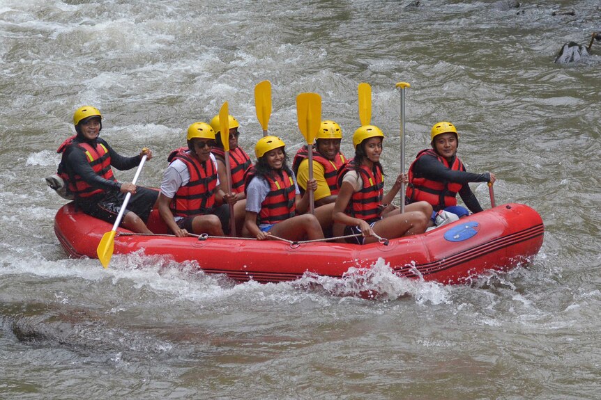 The Obama family are seen smiling as they sit in a raft in rapid waters in Bali.
