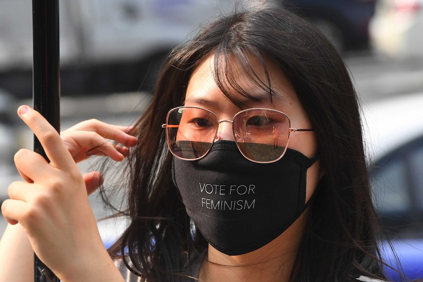 A South Korean women wearing a black mask that reads 'vote for feminism'.
