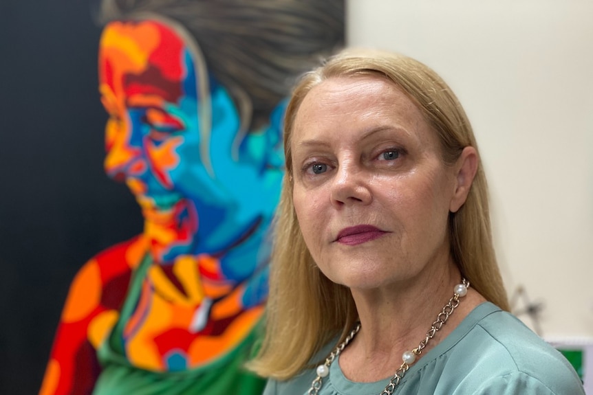 Woman with colourful painting in background