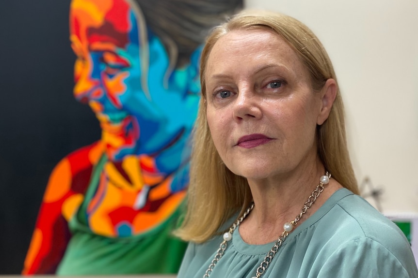 Woman with colourful painting in background