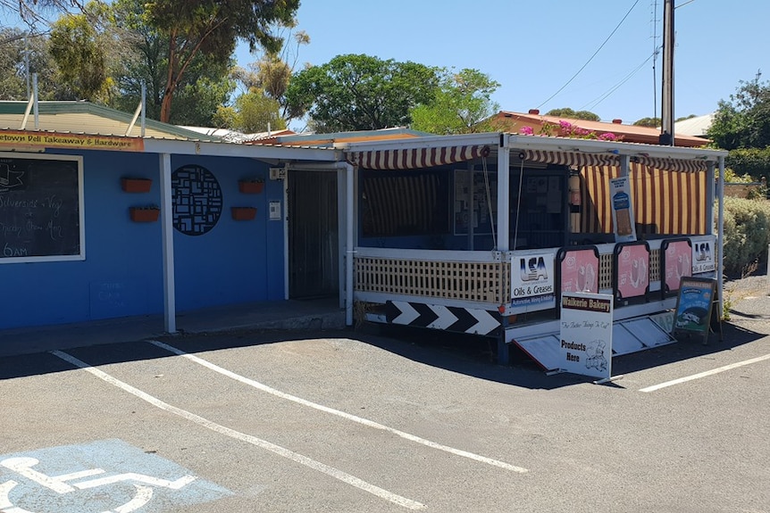 The front of a deli store with blue walls and orange striped blinds.