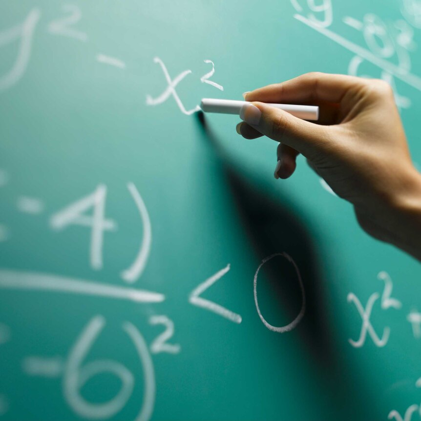 Hand writing math formulas on a blackboard