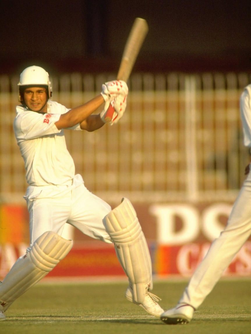 A man in cricket whites hits a ball with a bat