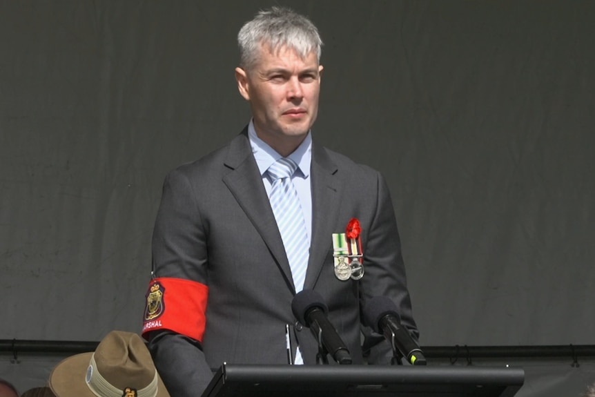 Thomas Brough stands during this year's Anzac Day service in Albany. He's wearing a suit.