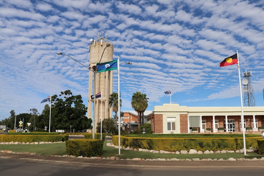 The Aboriginal and Torres Strait Islander flags fly in front of a white council building.