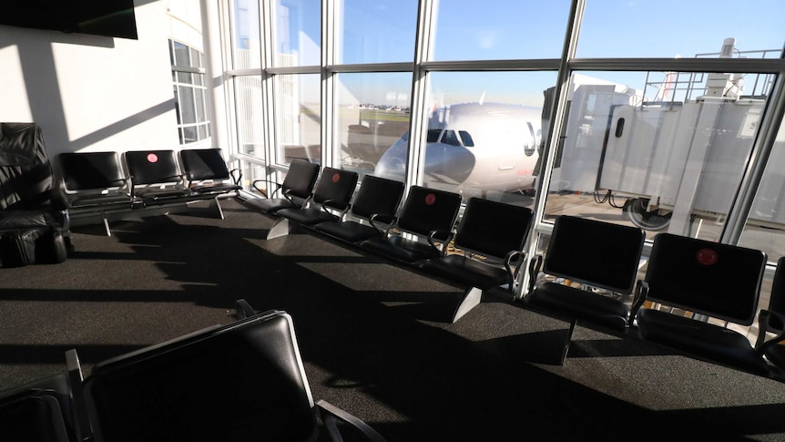 Photo of an empty airport terminal with a static plane.