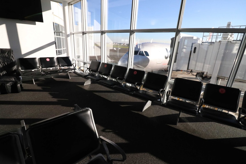 Photo of an empty airport terminal with a static plane.