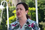 Queensland Premier speaking in front of microphones