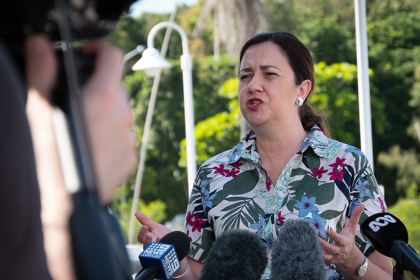 Queensland Premier speaking in front of microphones