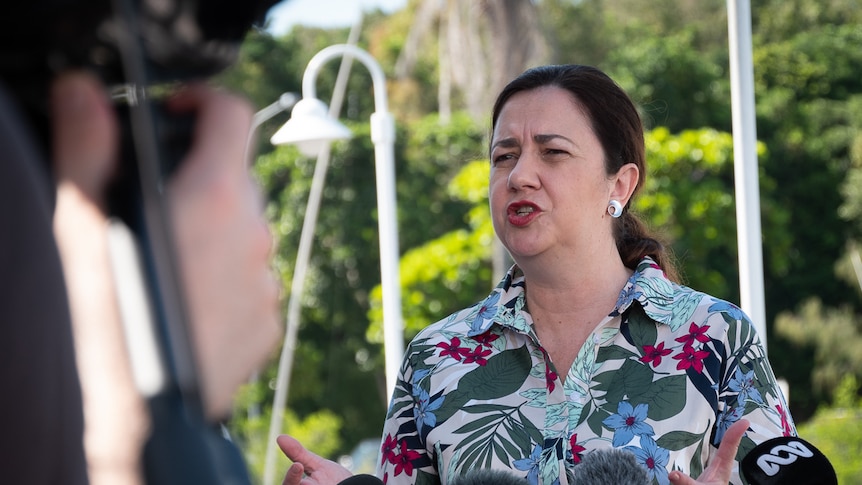 Queensland Premier speaking in front of microphones