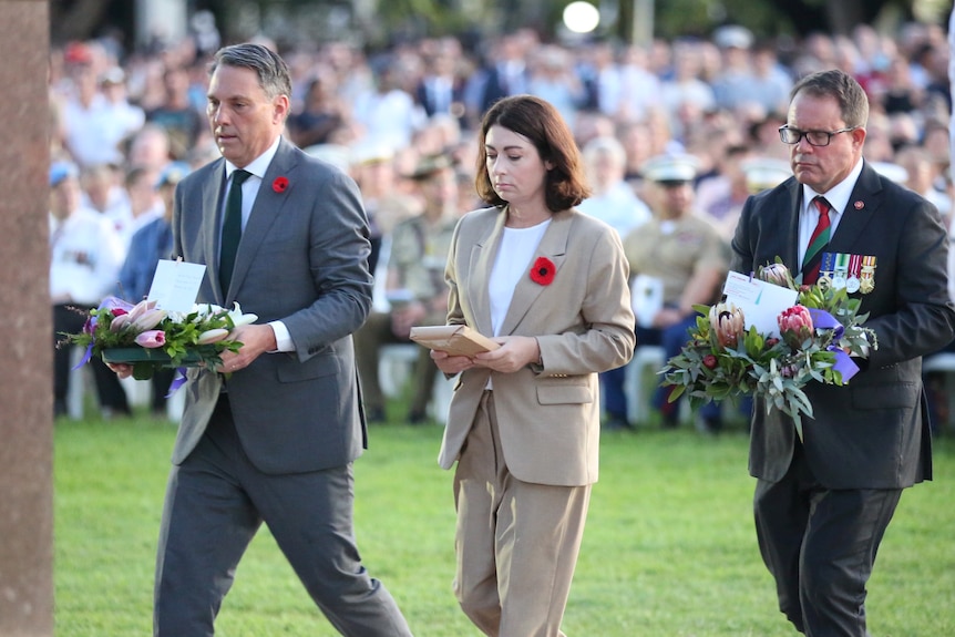 Richard Marles, Terri Butler and Luke Gosling lay a wreath at the Darwin dawn service. There is a seated crowd behind them.