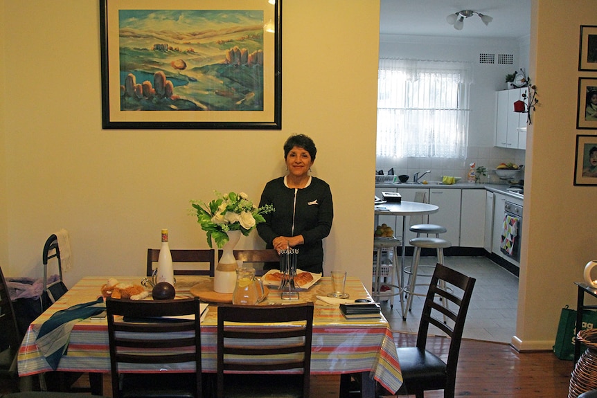 Eugenia Mora stands in her living room.