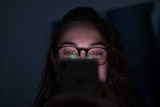 A woman look at her phone in the dark.