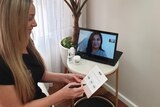 Nicole Bratis sits in front of a laptop at a beauty salon hosting a video call to a client.