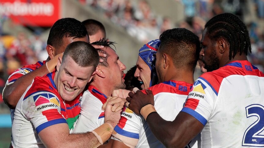 Knights players surround Mitchell Pearce to congratulate him after he scored a try for against the Warriors.