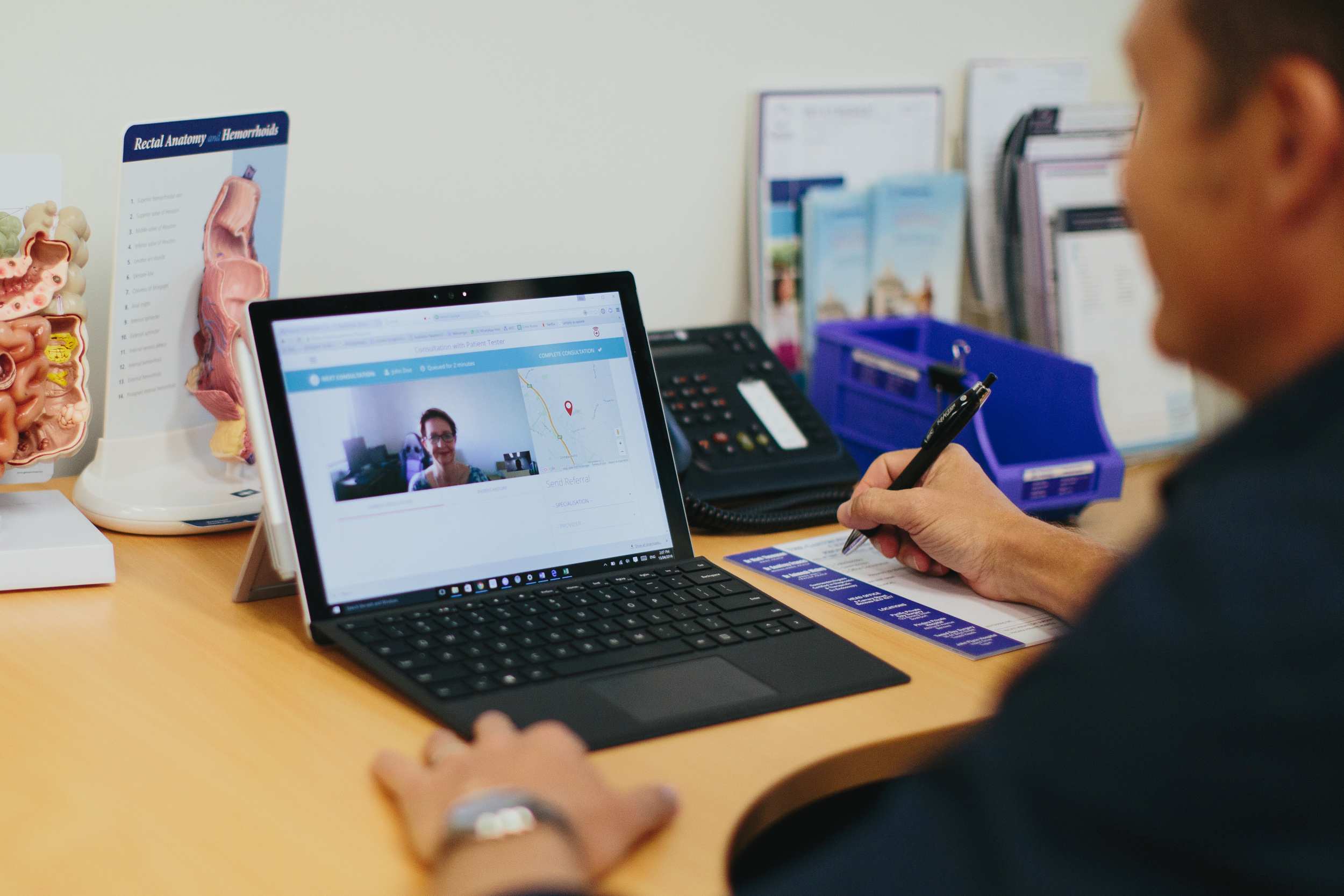 Man sits at desk looking at laptop screen, woman is displayed on screen